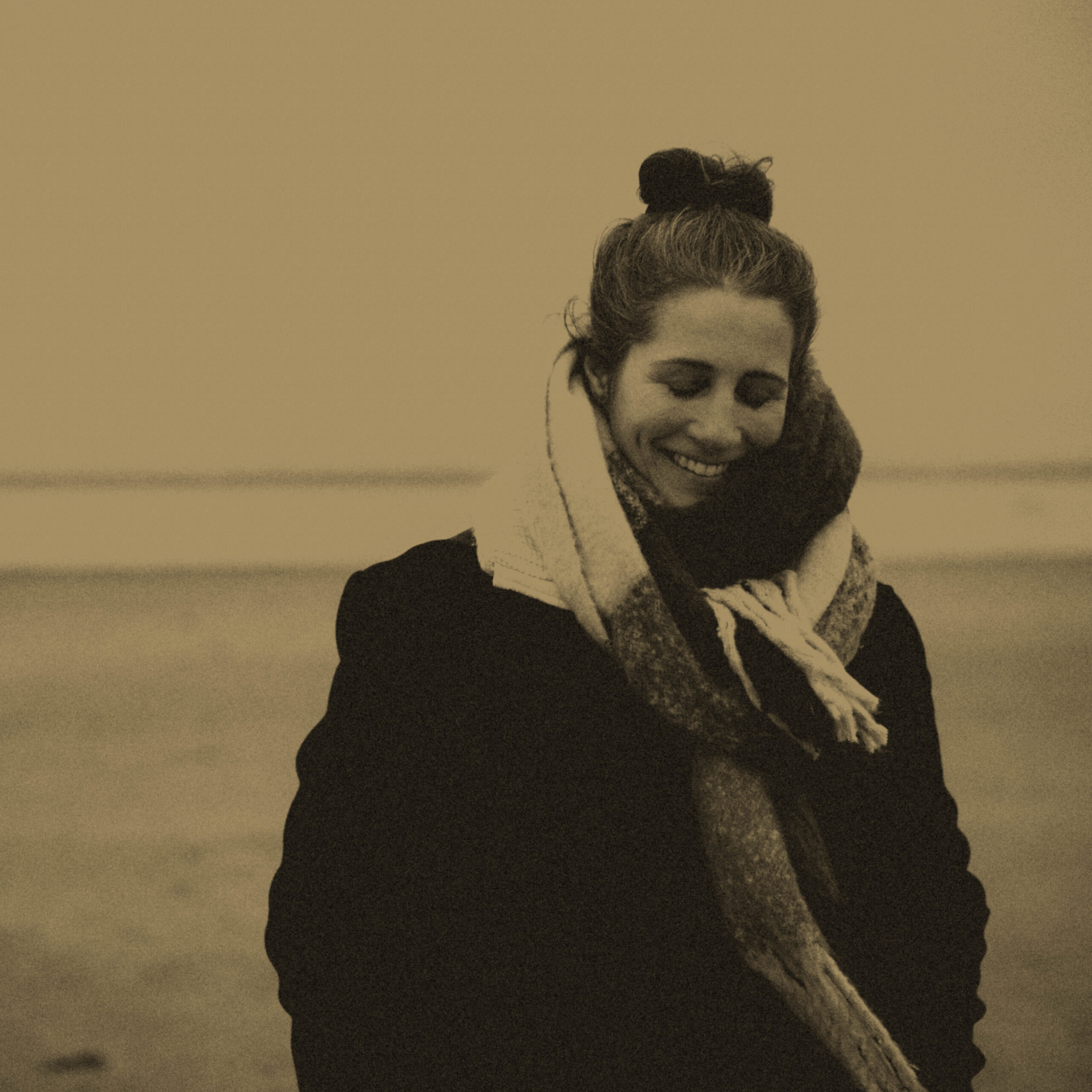 Isabell läuft im Winter am Strand u d lächelt mit geschlossenen Augen in sich hinein.